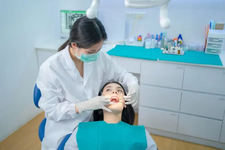At Andros Orthodontics in Pasco, WA, a dentist wearing a mask and gloves examines a reclined patient in the dental chair.