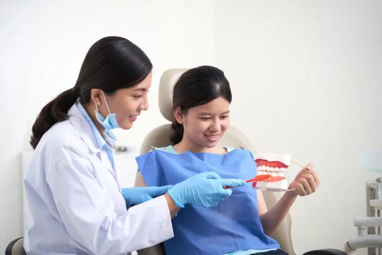 At Andros Orthodontics in Pasco, WA, a dentist shows a young patient the correct toothbrushing technique using a dental model and toothbrush.