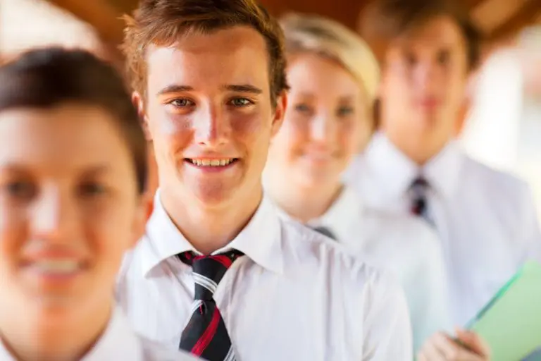Four young people in white shirts and striped ties stand confidently in a line, smiling at the camera—possibly showcasing the results of Incognito Brackets from Andros Orthodontics in Pasco, WA.