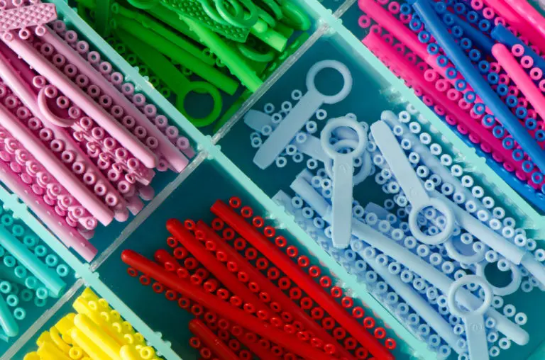 Colorful plastic Damon Brackets—including pink, green, blue, and red—are neatly sorted in a storage container at Andros Orthodontics in Pasco, WA.