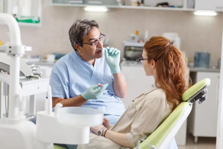 At Andros Orthodontics in Pasco, WA, a dentist wearing gloves explains dental care to a patient seated in the clinic's chair.