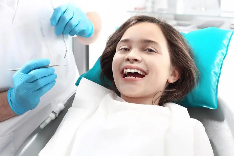 Child smiling while sitting in a dental chair, appearing happy during a dental check-up - Overbite vs Underbite in Pasco, WA.