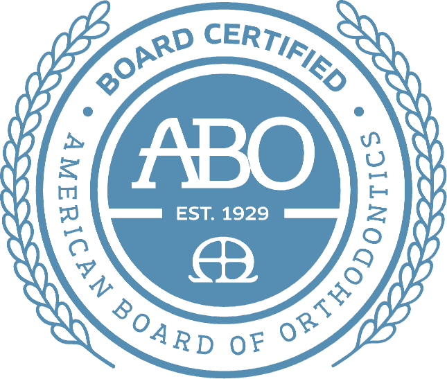 Blue badge for Andros Orthodontics in Pasco, WA: “BOARD CERTIFIED”, “AMERICAN BOARD OF ORTHODONTICS”, “ABO EST. 1929”, laurel border.
