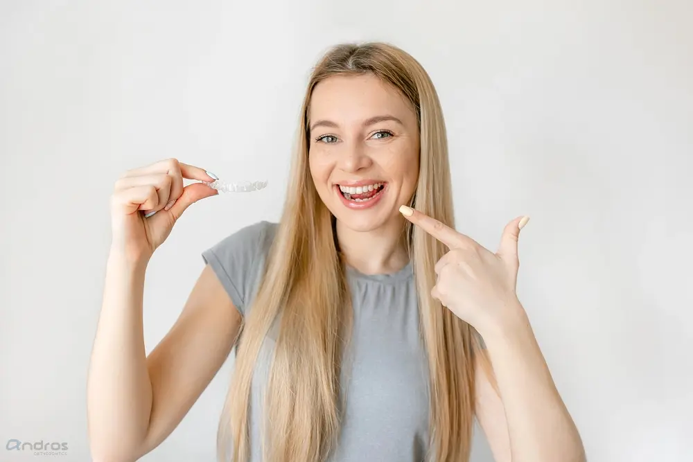 a woman pointing her teeth holding clear aligners - Alternatives to Braces in Pasco, WA 