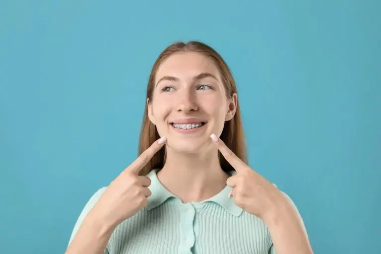 girl pointing her metal braces light blue background - Alternatives to Braces in Pasco, WA