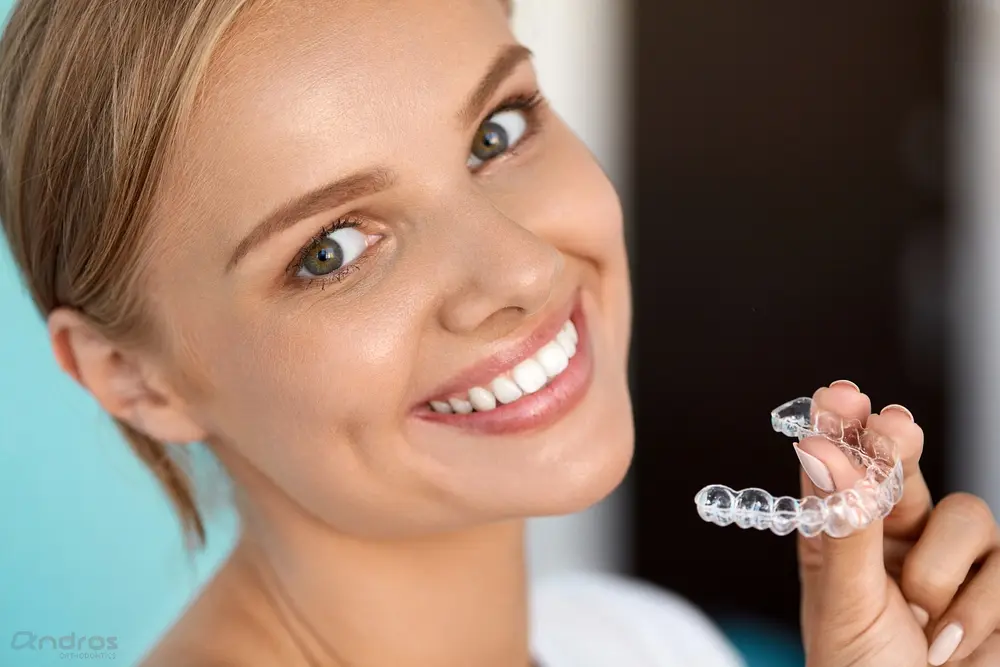 smiling woman with white teeth holding invisalign clear aligners - How Does Invisalign Work in Pasco, WA