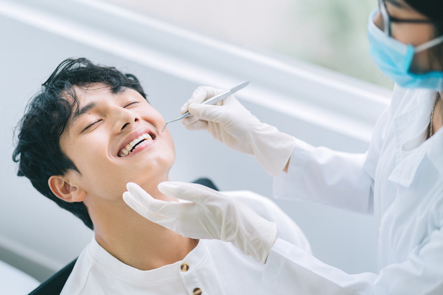 At Andros Orthodontics in Pasco, WA, a dentist wearing gloves and a mask examines a patient's metal braces with dental tools in a well-lit clinic.