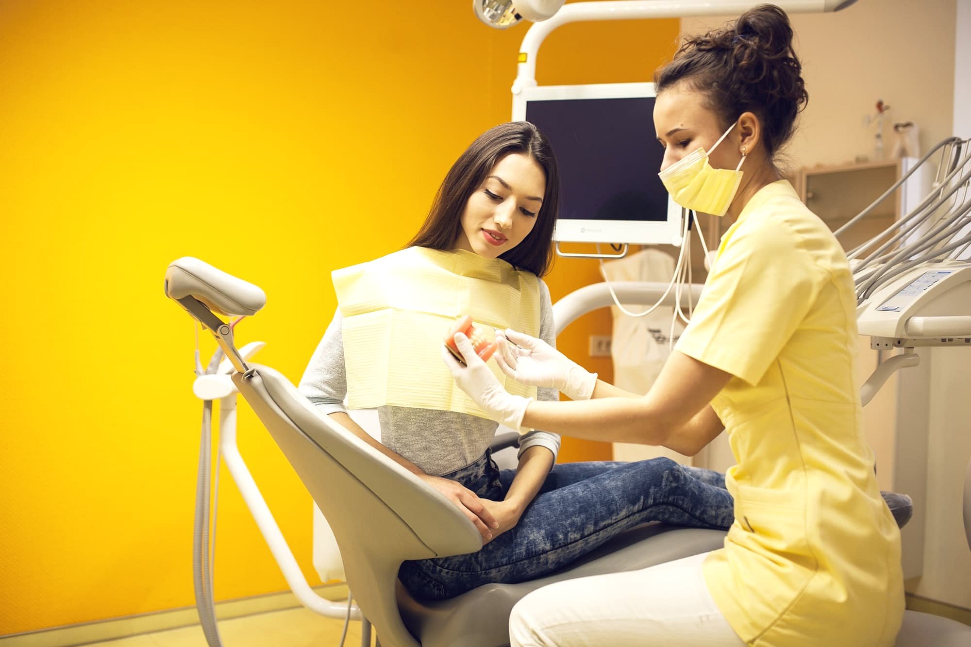 At Andros Orthodontics in Pasco, WA, a dental professional in a yellow uniform and mask prepares a female patient for a procedure, emphasizing the importance of orthodontic insurance plans for comprehensive care.