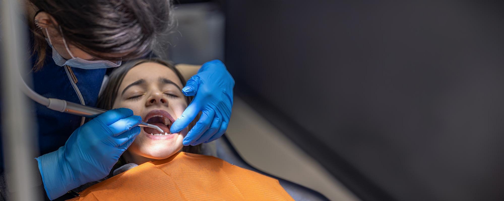 At Andros Orthodontics in Pasco, WA, a dentist wearing gloves and a mask uses dental tools to examine a patient’s open mouth, likely assessing the fit of a MARPE appliance.