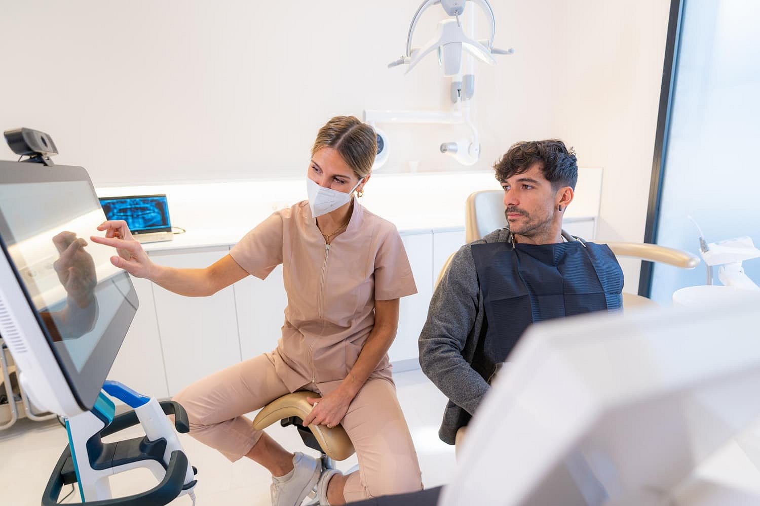At Andros Orthodontics in Pasco, WA, a dental professional discusses Invisalign Payment Plan options with a male patient while pointing at a monitor.