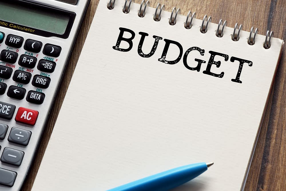 At Andros Orthodontics in Pasco, WA, a calculator, blue pen, and notepad labeled "BUDGET" on a wooden surface help you easily map out your braces payment plan.