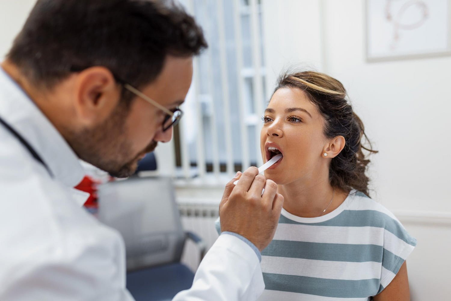 At Andros Orthodontics in Pasco, WA, a doctor uses a tongue depressor to examine a woman's throat for signs of an underbite.