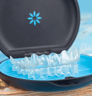 Clear dental aligners rest in a black and blue case on a wooden surface—ideal for those exploring Invisalign Payment Plan options with Andros Orthodontics in Pasco, WA.