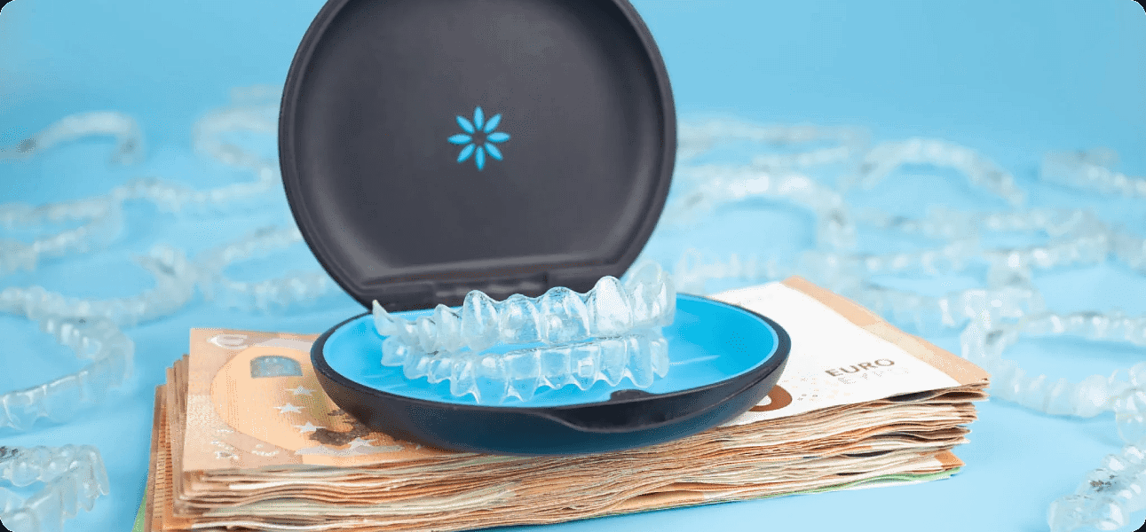 In this image, a blue dental aligner case with clear aligners rests on a stack of Euro banknotes, subtly emphasizing Invisalign cost at Andros Orthodontics in Pasco, WA. Additional aligners are scattered across the blue background.