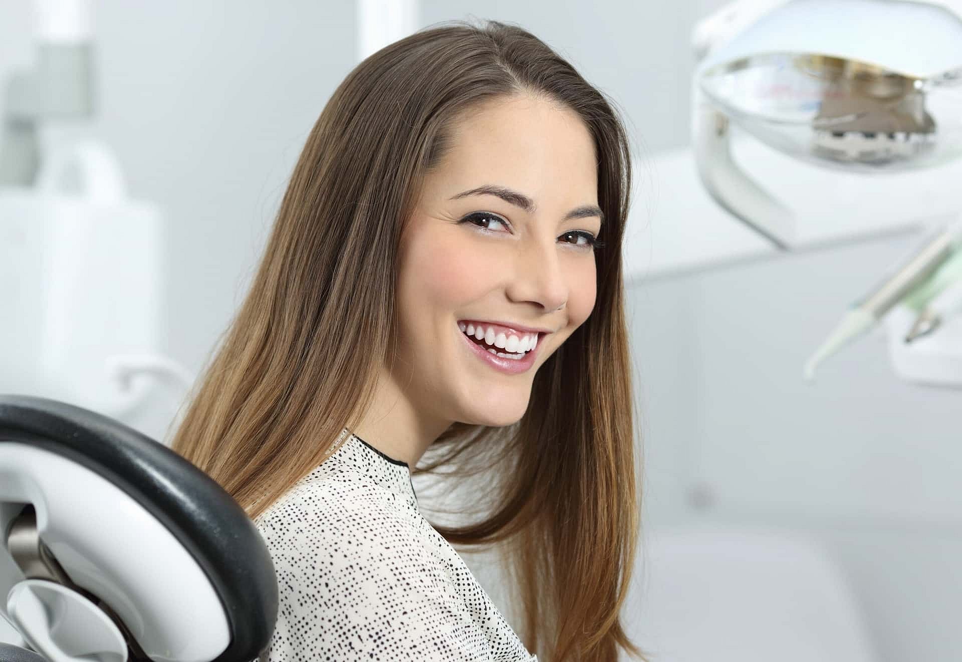 A woman with long brown hair smiles in a dental chair, surrounded by equipment, ready for her adult orthodontics consultation at Andros Orthodontics in Pasco, WA.