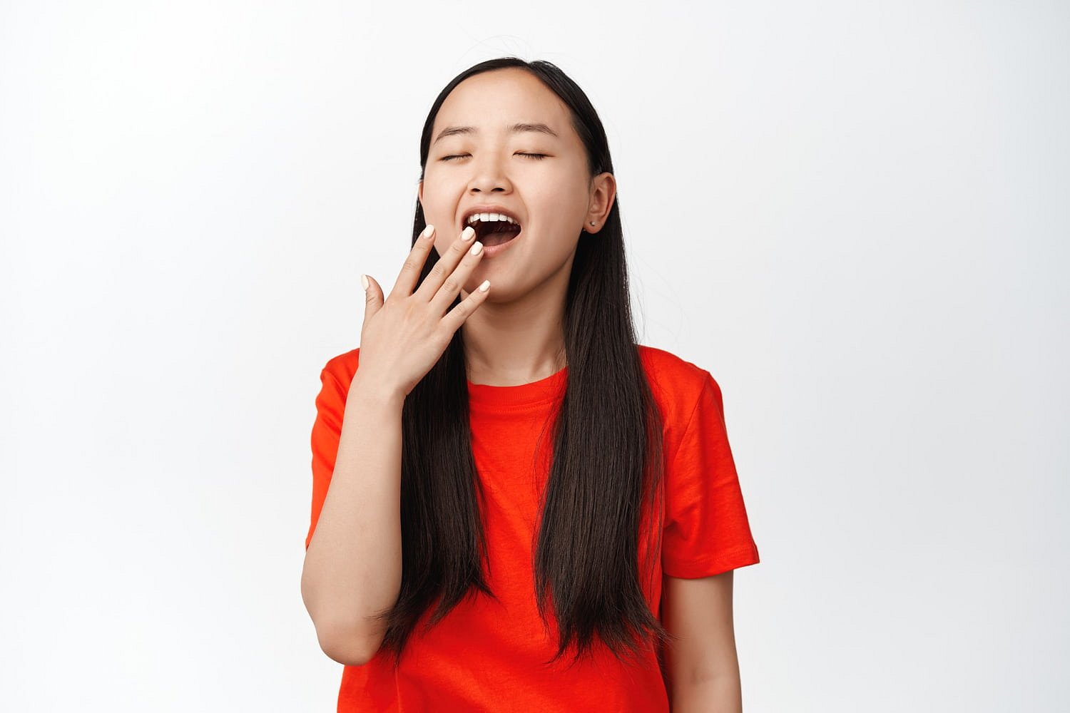 A young person with long dark hair and a red t-shirt appears to yawn with eyes closed and hand near mouth, resembling a typical mouth breather—an issue Andros Orthodontics addresses in Pasco, WA, against a plain white background.