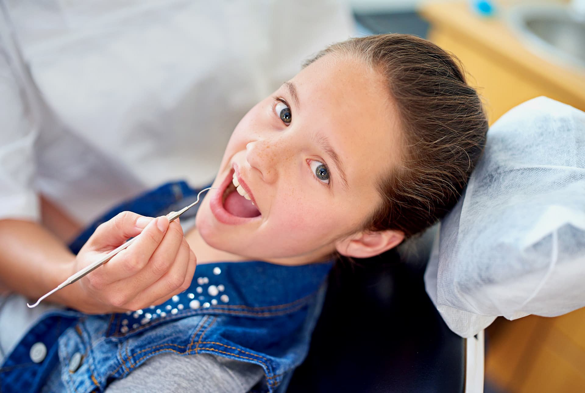 A children’s orthodontist at Andros Orthodontics in Pasco, WA examines a child’s teeth with a dental tool as the child sits in the dental chair.