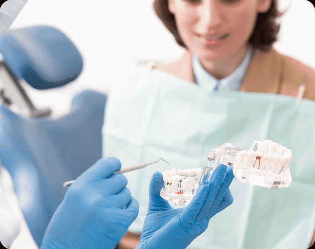 At Andros Orthodontics in Pasco, WA, a dentist wearing blue gloves uses a dental model and tool to explain jaw surgery procedures to a patient in the dental chair.