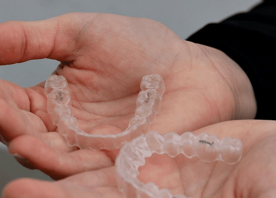 Considering an Invisalign payment plan for a confident new smile, a person holds two clear aligners at Andros Orthodontics in Pasco, WA.