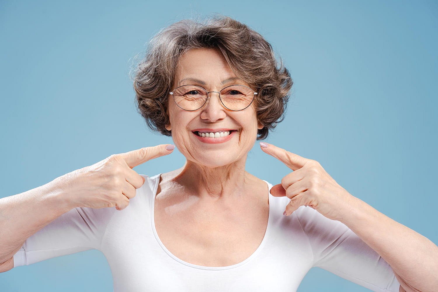 A confident older woman with curly gray hair smiles, thanks to her orthodontic insurance plan from Andros Orthodontics in Pasco, WA.