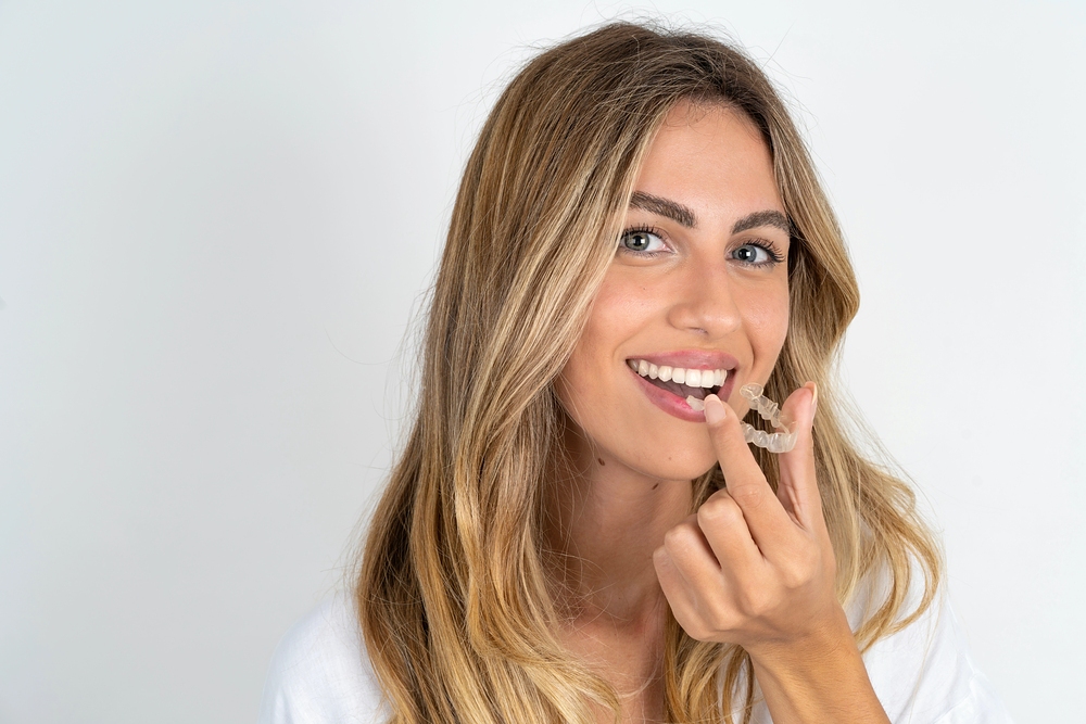young caucasian business woman wearing white shirt background holding invisalign clear aligners - Can Invisalign Fix Overbite in Pasco, WA.