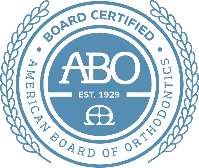 Blue badge for Andros Orthodontics in Pasco, WA: “BOARD CERTIFIED”, “AMERICAN BOARD OF ORTHODONTICS”, “ABO EST. 1929”, laurel border.